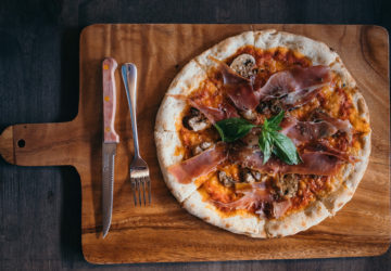 Pizza with parma ham and mushrooms, mozzarella, tomato, oregano, and extra virgin olive oil