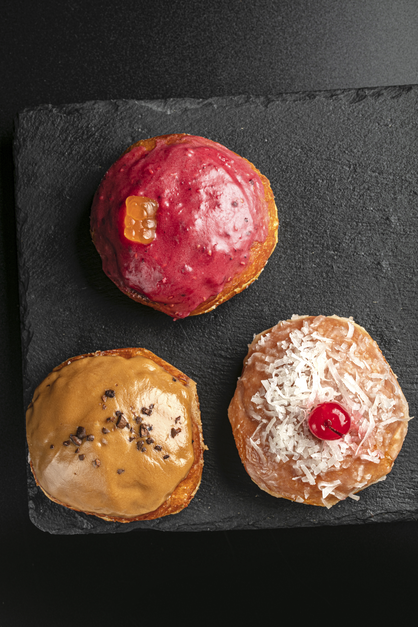 Poison doughnut trio of Berries Yakult, Piña Colada, and Irish Coffee
