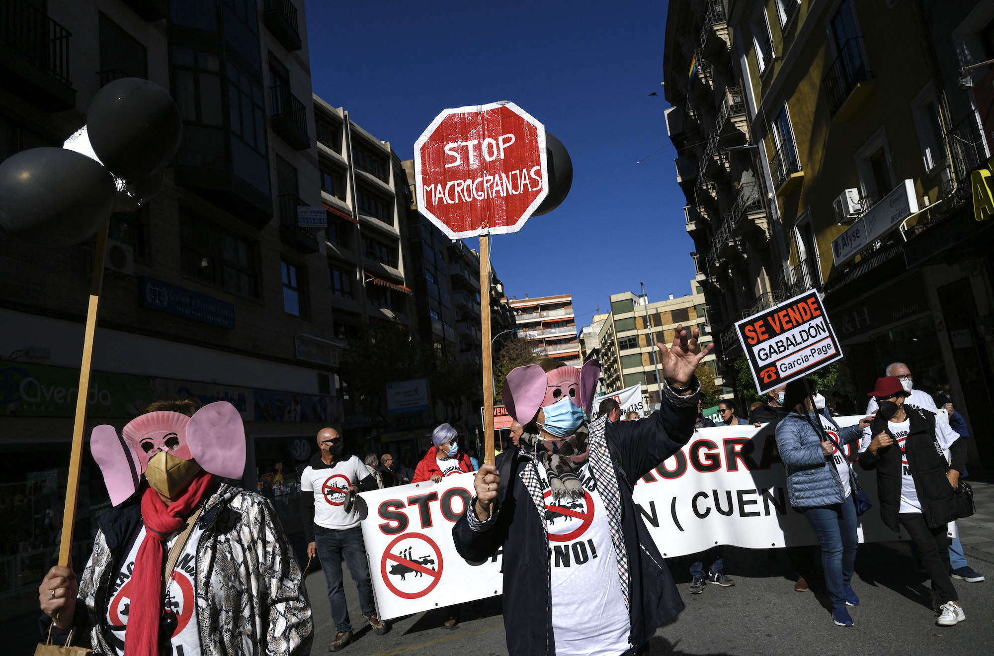 A protester wearing a pig mask holds a sign reading "Stop macrofarms" during a demonstration called by the "Pueblos Vivos Cuenca" association to denounce the permits for new intensive livestock farms and to demand extensive, social and environmental sustainable livestock farming, in Cuenca
