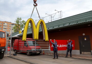 Workers use a crane to dismantle the McDonald's Golden Arches