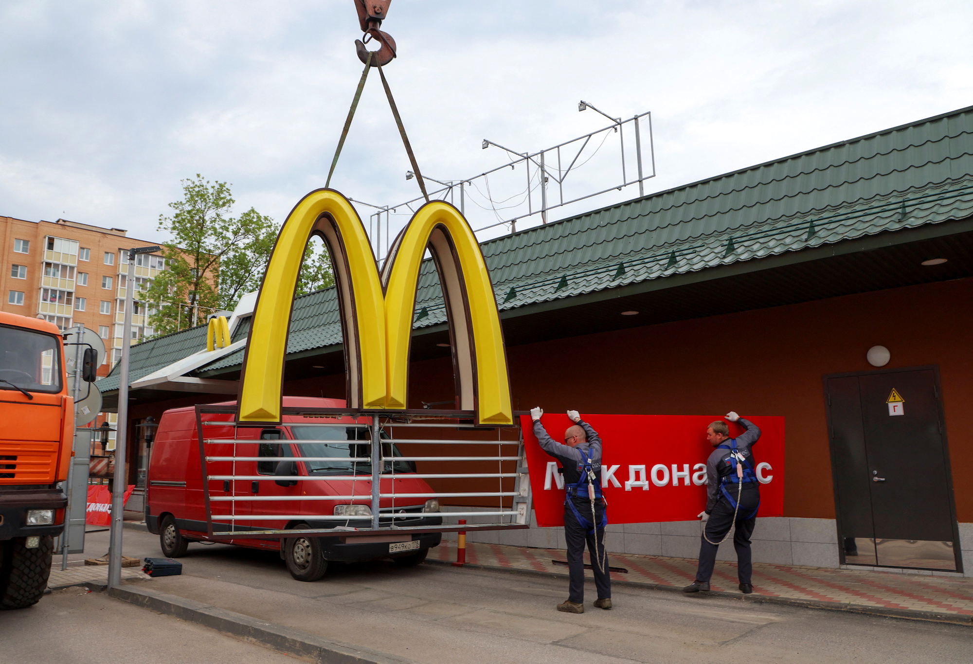 Workers use a crane to dismantle the McDonald's Golden Arches