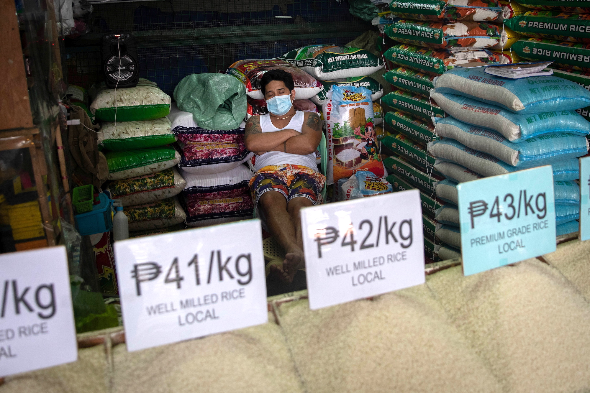 A vendor wearing a face mask for protection against the coronavirus disease (COVID-19) sleeps in a stall selling rice at a public market in Quezon City, Metro Manila, Philippines