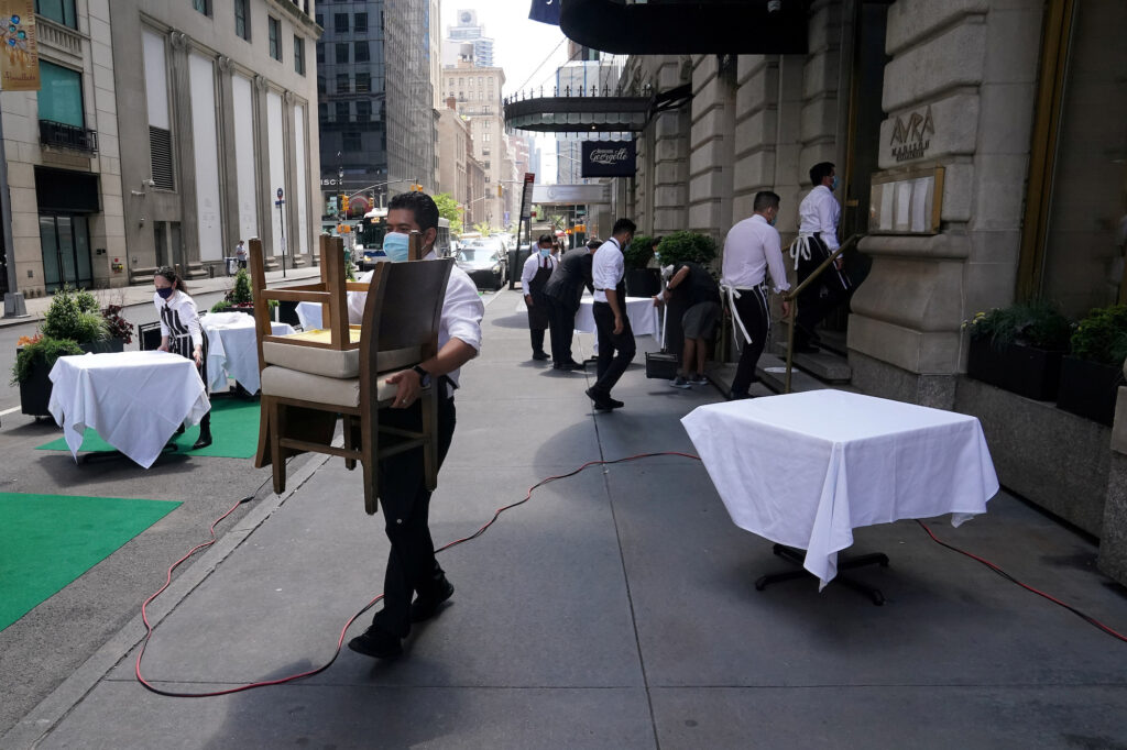 Ready for the new normal? A waiter sets up tables in front of a restaurant on a street on the first day of the phase two reopening of businesses following the outbreak of the coronavirus disease (COVID-19), in the Manhattan borough of New York City, New York