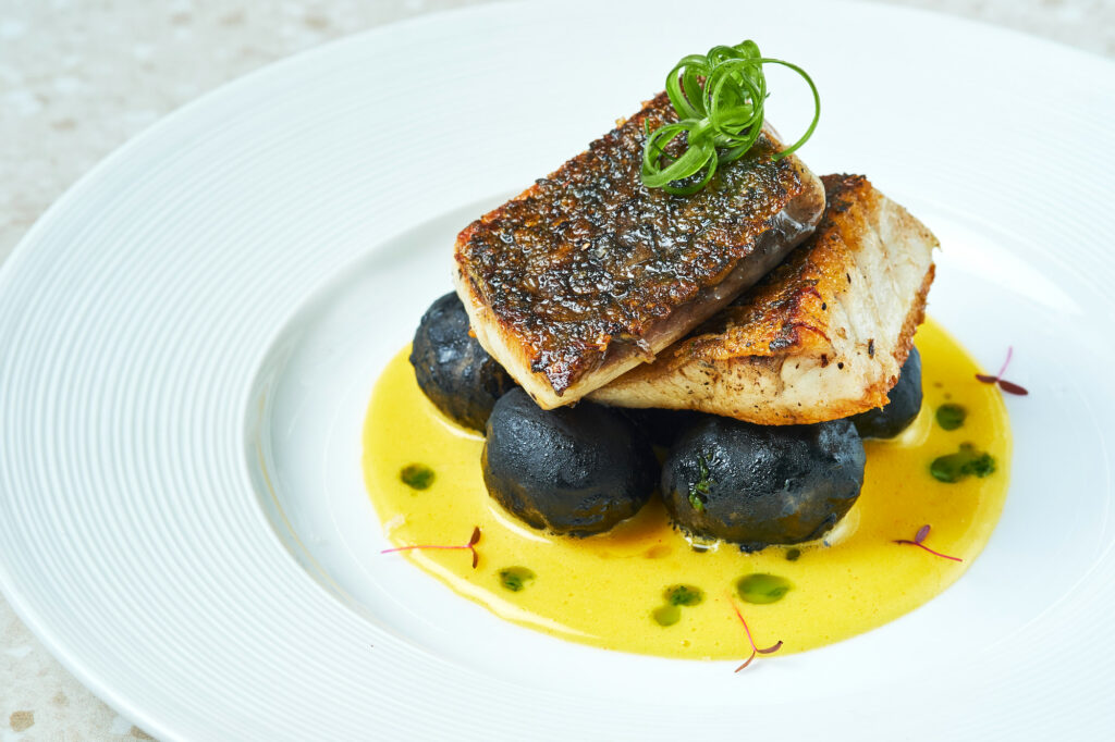 Pescado del Dia or grilled catch of the day with marble squid ink potatoes, hollandaise sauce, and EVOO herbs