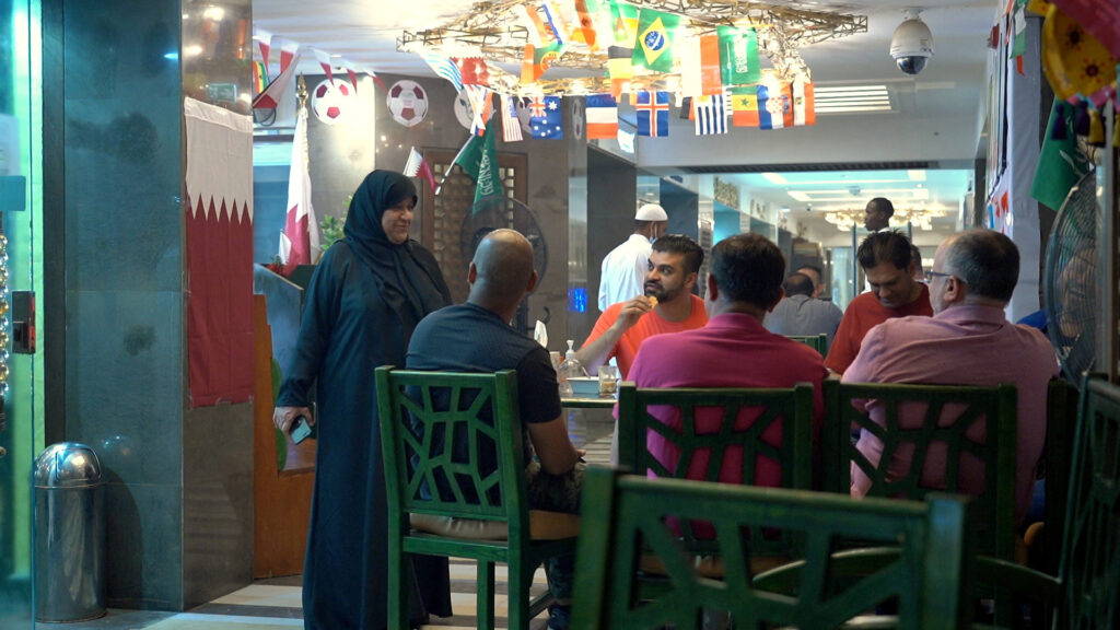 Shams al-Qassabi, the owner of the Shay al-Shamous restaurant, talks with a group of United States football supporters