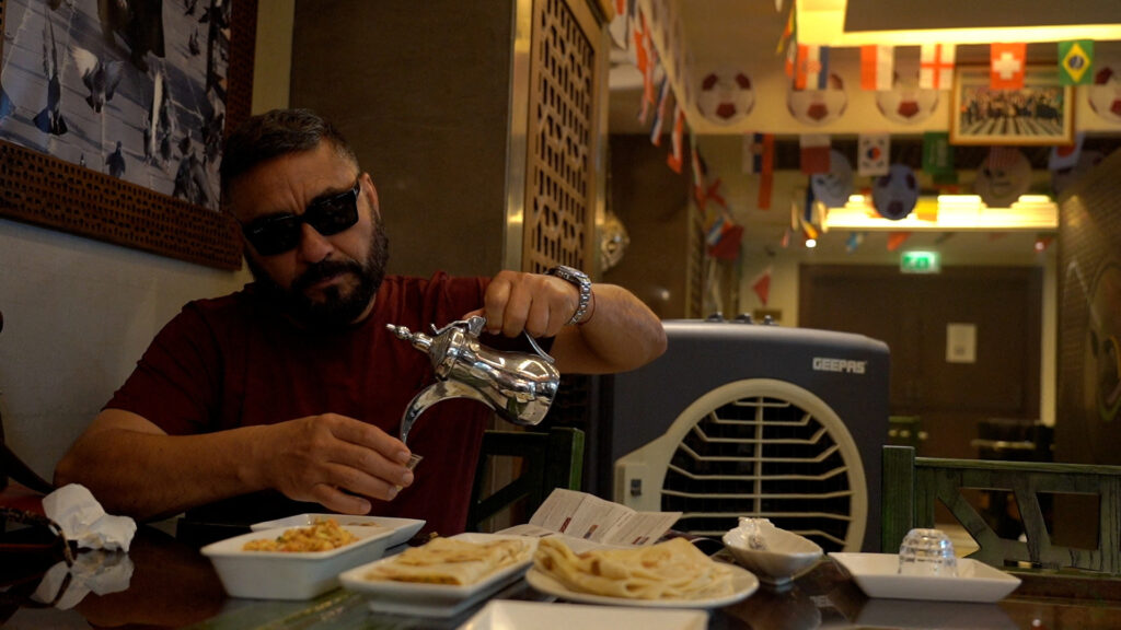 A Mexican football fan pours tea while he eats in the Shay al-Shamous restaurant