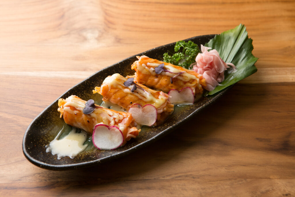 Seared Salmon: Shredded crab stick and crispy tempura bits mixed in spicy mayo, wrapped in thinly sliced salmon, topped with wasabi mayo, lightly torched and garnished with orange tobiko