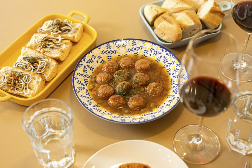 A hot spread of gulas on toasted bread and albondigas with green peas