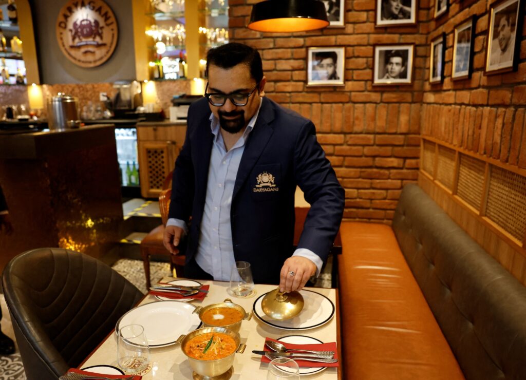 Amit Bagga, CEO of Daryaganj restaurant, shows a freshly prepared butter chicken dish and the lentil dish Dal Makhani inside Daryaganj restaurant at a mall, in Noida, India, January 23, 2024. REUTERS/Sahiba Chawdhary