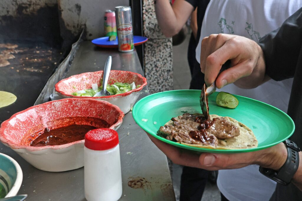 Customers are served tacos at Taqueria restaurant El Califa de Leon in Mexico City on May 15, 2024. A hole-in-the-wall taqueria is among the first restaurants in Mexico to be awarded a star by the prestigious Michelin Guide -- an accomplishment its owner credits to "love and effort". (Photo by Silvana FLORES / AFP)